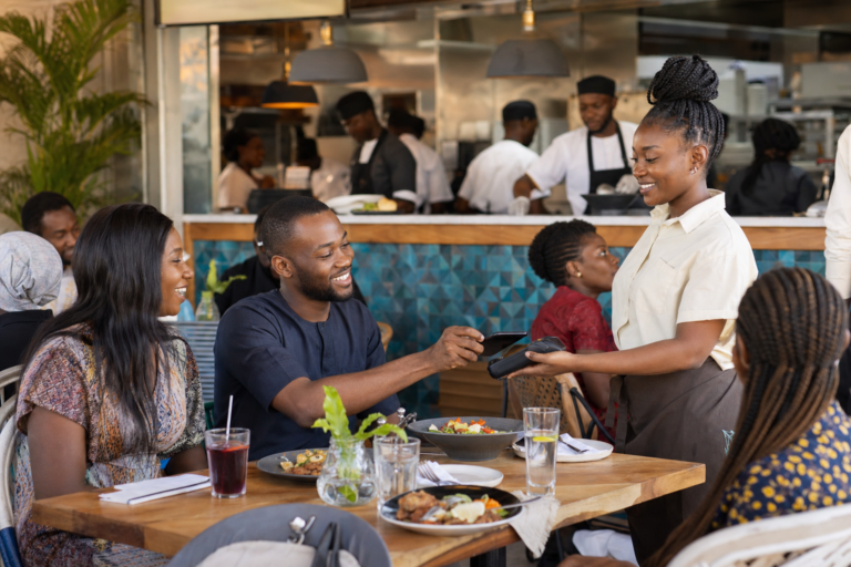Customers making a digital payment at a busy modern restaurant in Lagos